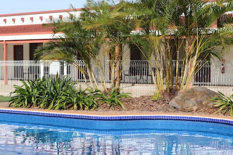 Una piscina al aire libre, sombrillas, sillones reclinables de piscina