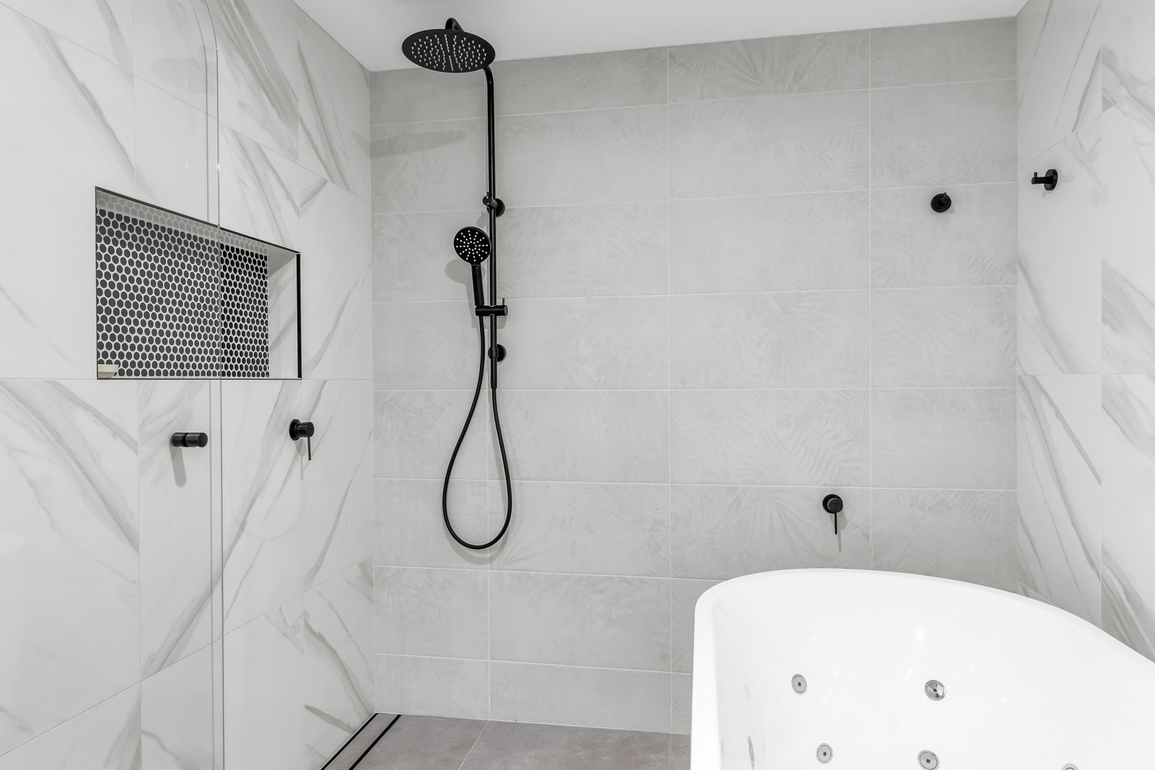 A modern bathroom with a freestanding bathtub, a handheld showerhead, and a wall-mounted control panel.
