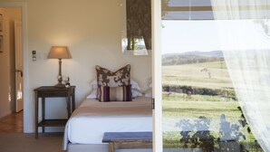 A bedroom with a bed, bedside table, lamp, and a window with a view of a field. - Rosby Guesthouse (Eurunderee)