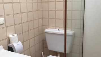A bathroom with a toilet, a paper towel dispenser, and a white sink.