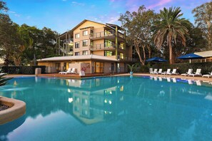 Guests can enjoy stunning views from the balconies, overlooking a serene pool area surrounded by lush greenery and palm trees.