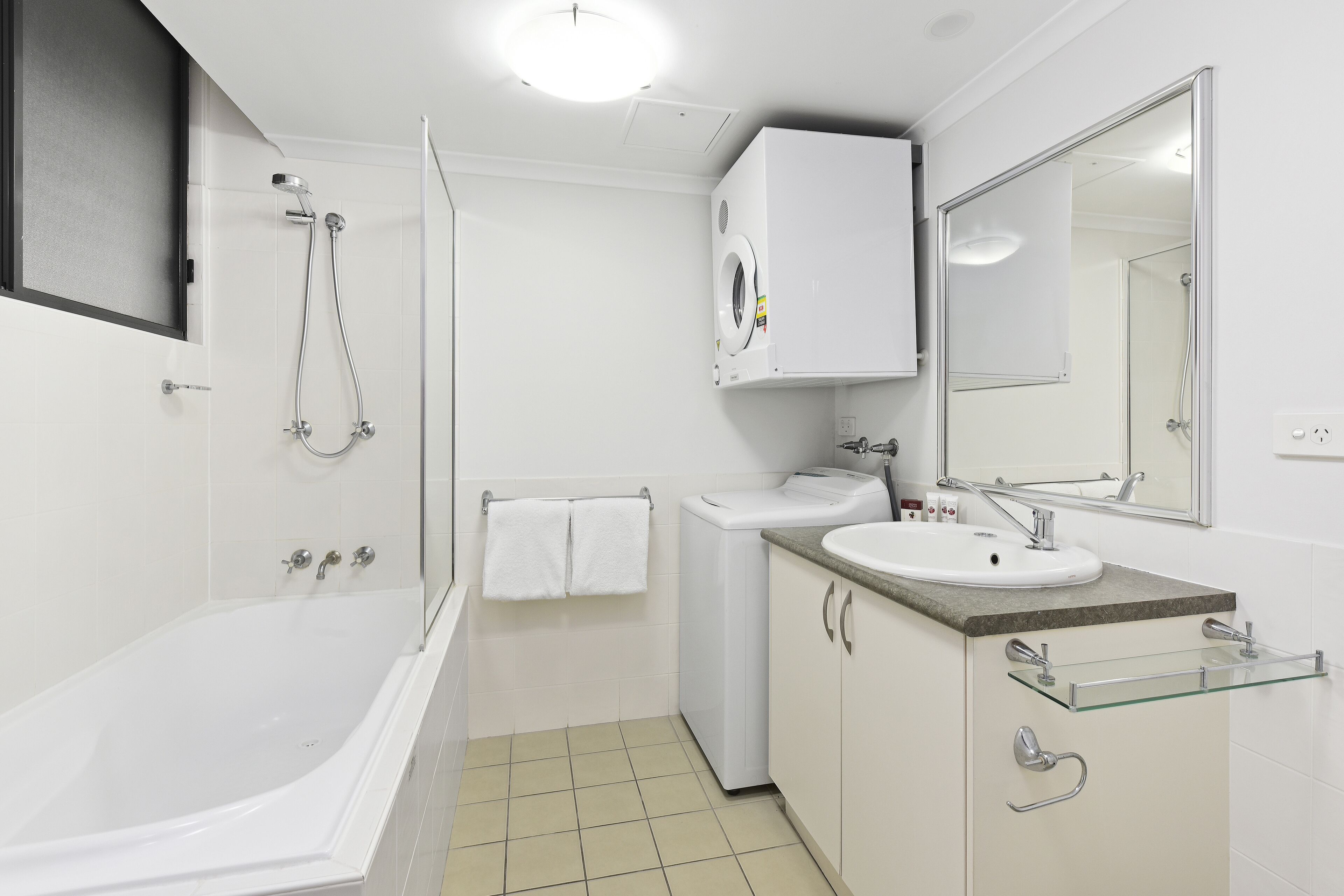 A modern bathroom with a bathtub, a glass shower enclosure, a sink with a mirror, and a toilet.