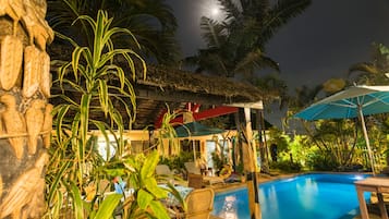 Una piscina al aire libre, sombrillas, sillones reclinables de piscina