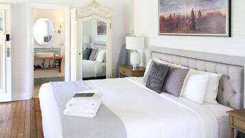 Ein Hotelzimmer mit einem großen Bett, einem Badezimmer mit Waschbecken und einem Bild an der Wand.