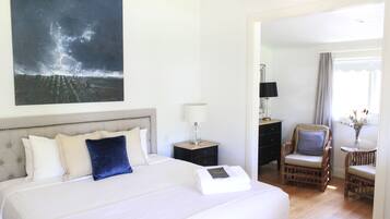 A hotel room with a large bed, a nightstand with a lamp, a chair, and a painting of a stormy sky.