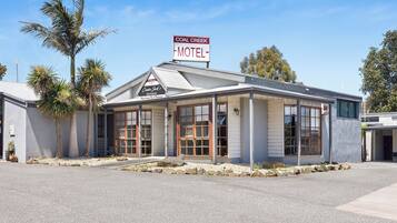 Un motel avec un panneau indicateur, une véranda couverte et un palmier.