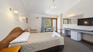 Une chambre d’hôtel avec un lit, un bureau, une télévision et une fenêtre avec des rideaux.