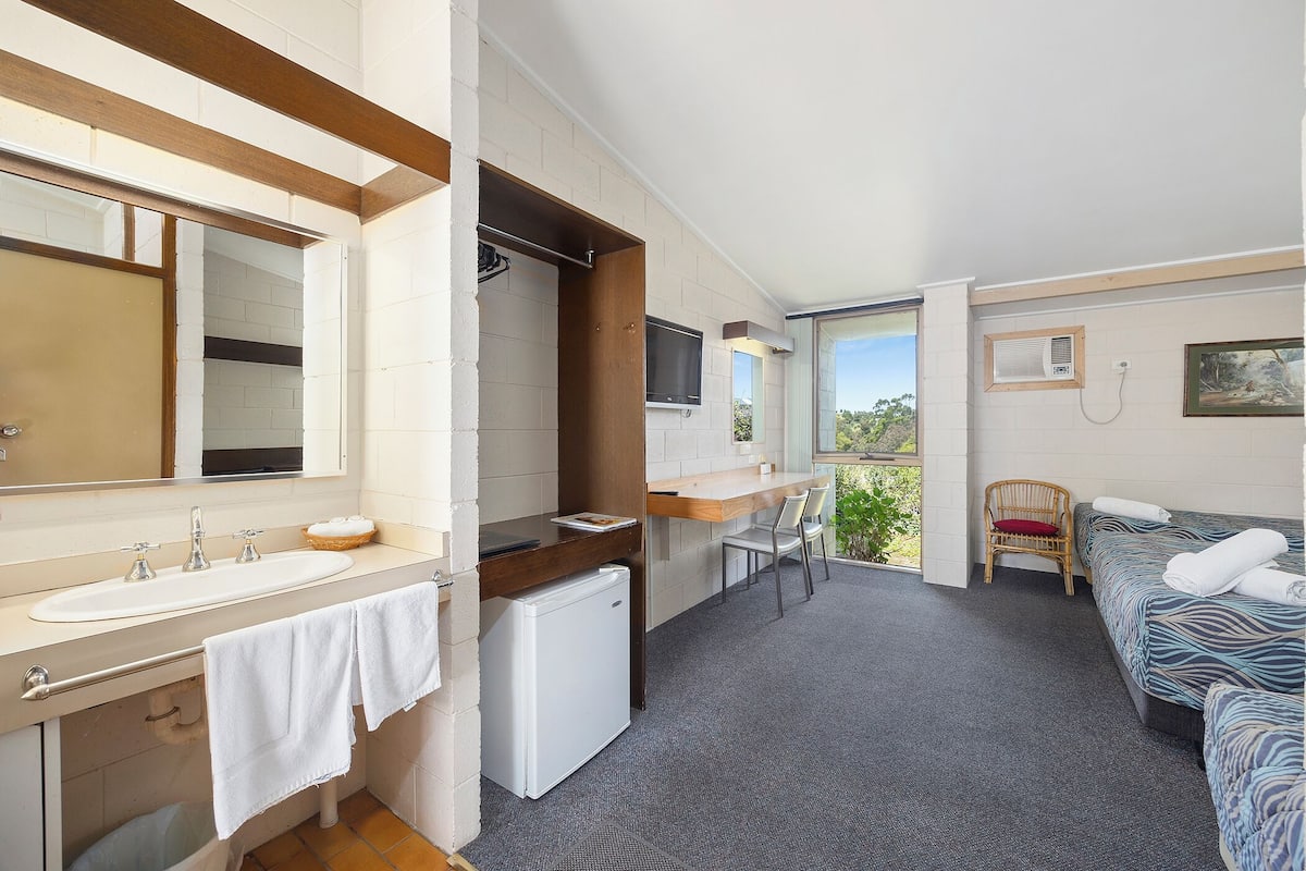 Une chambre d’hôtel avec une grande salle de bain, une petite kitchenette, un lit et un balcon avec vue.