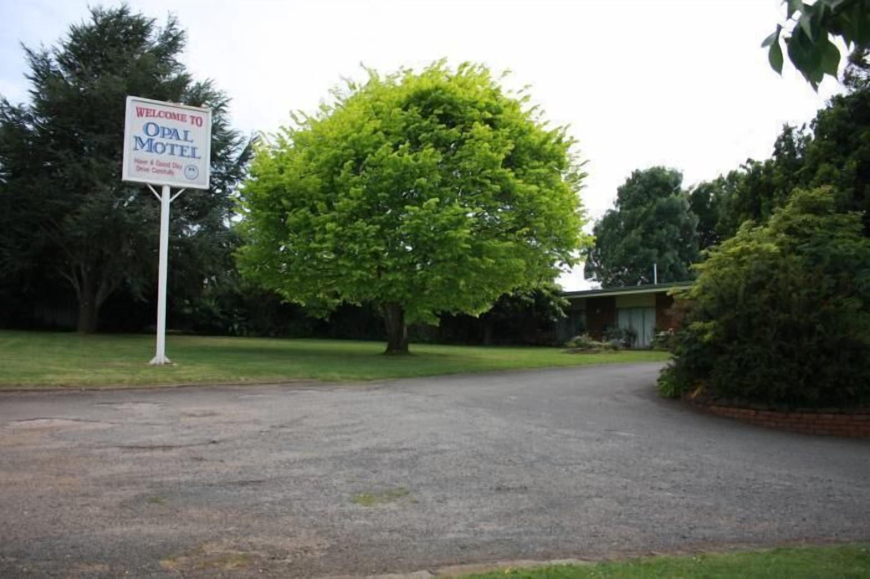 Une enseigne accueillante pour l’Opal Motel, une allée pavée et un grand arbre.