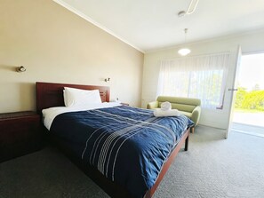 Een hotelkamer met een bed, een stoel, een raam en een deur.