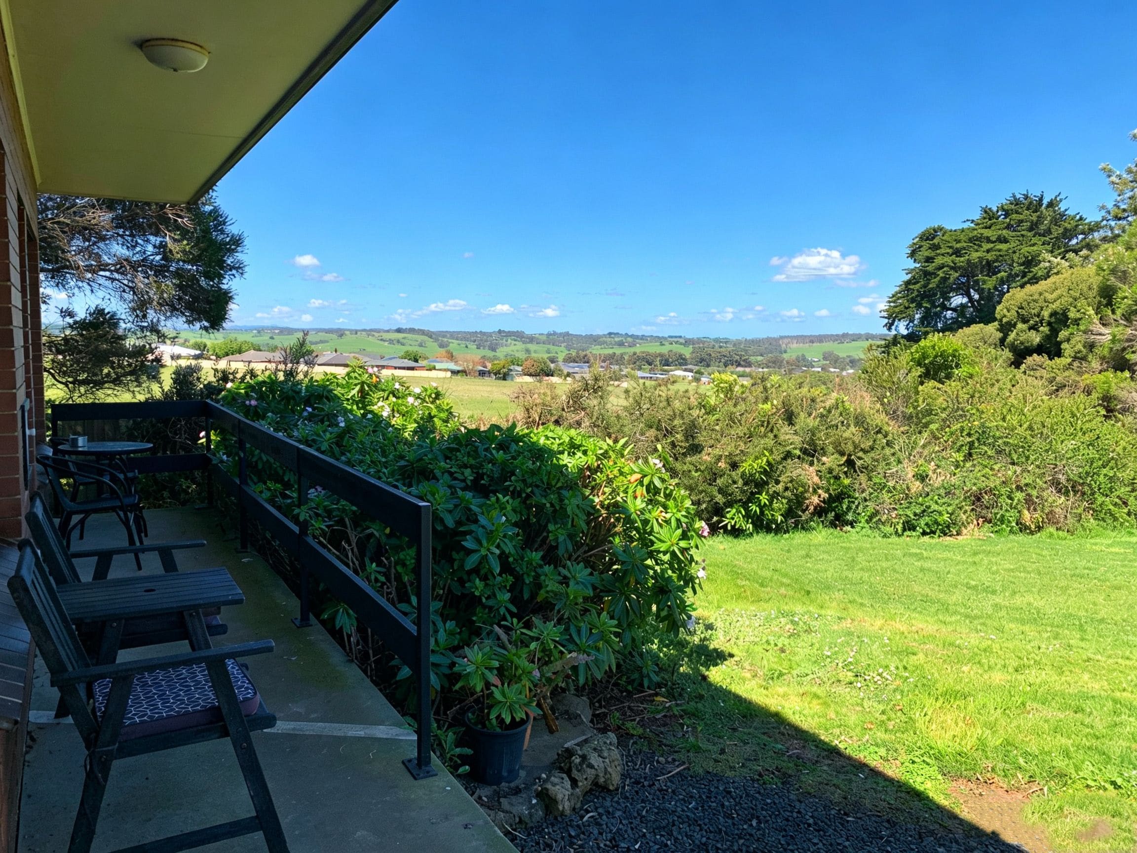 A patio with outdoor seating and a view of a green landscape.