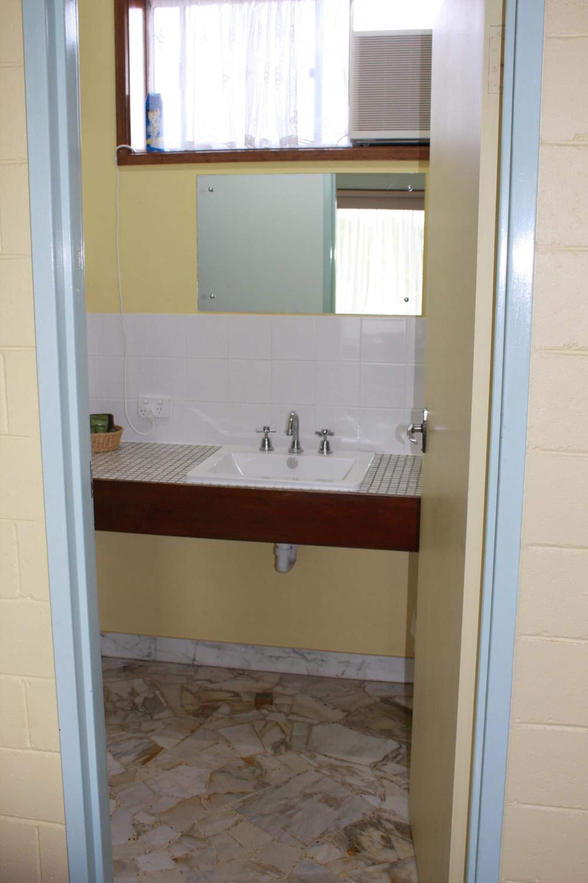 A bathroom with a double sink, a mirror above the sink, and a window with curtains.