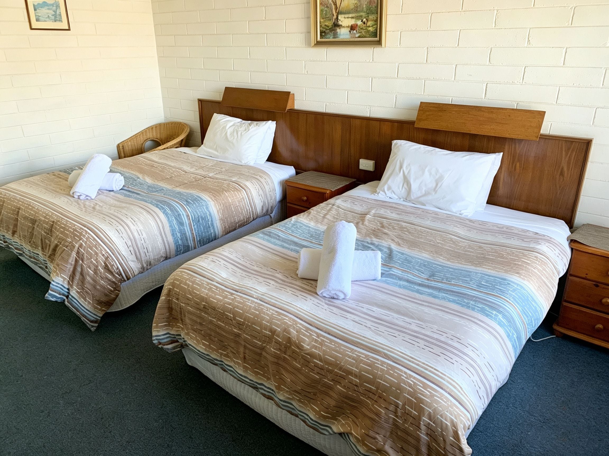 Two twin beds with striped bedding, wooden headboards, and bedside tables with lamps.