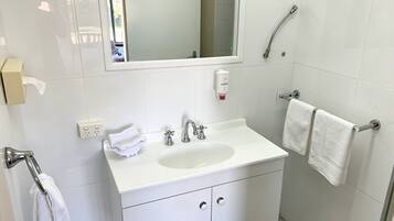 A bathroom with a white sink, mirror, and towel rack.
