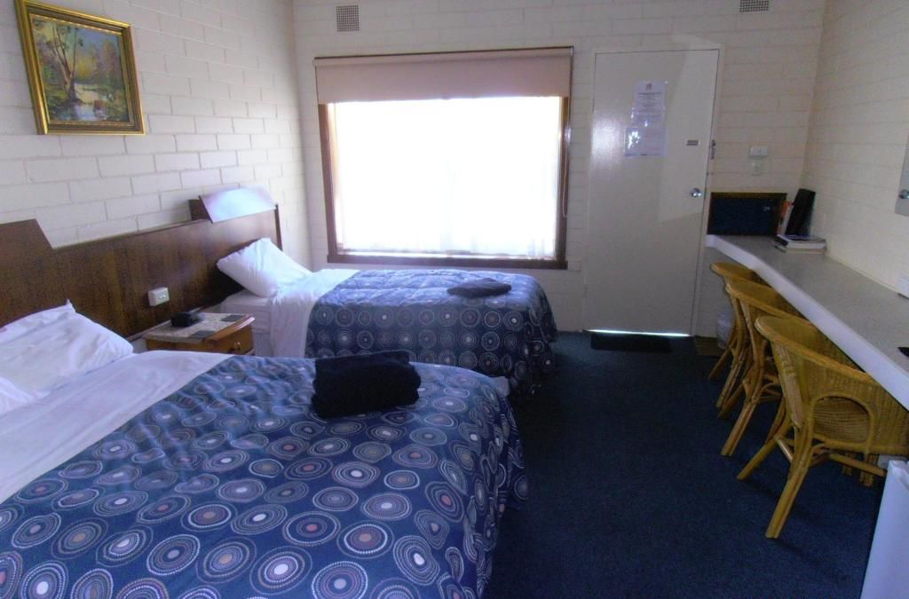 A room with two beds, a desk, and a window.