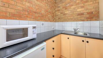 Una cocina con microondas blanco, un lavabo y armarios.