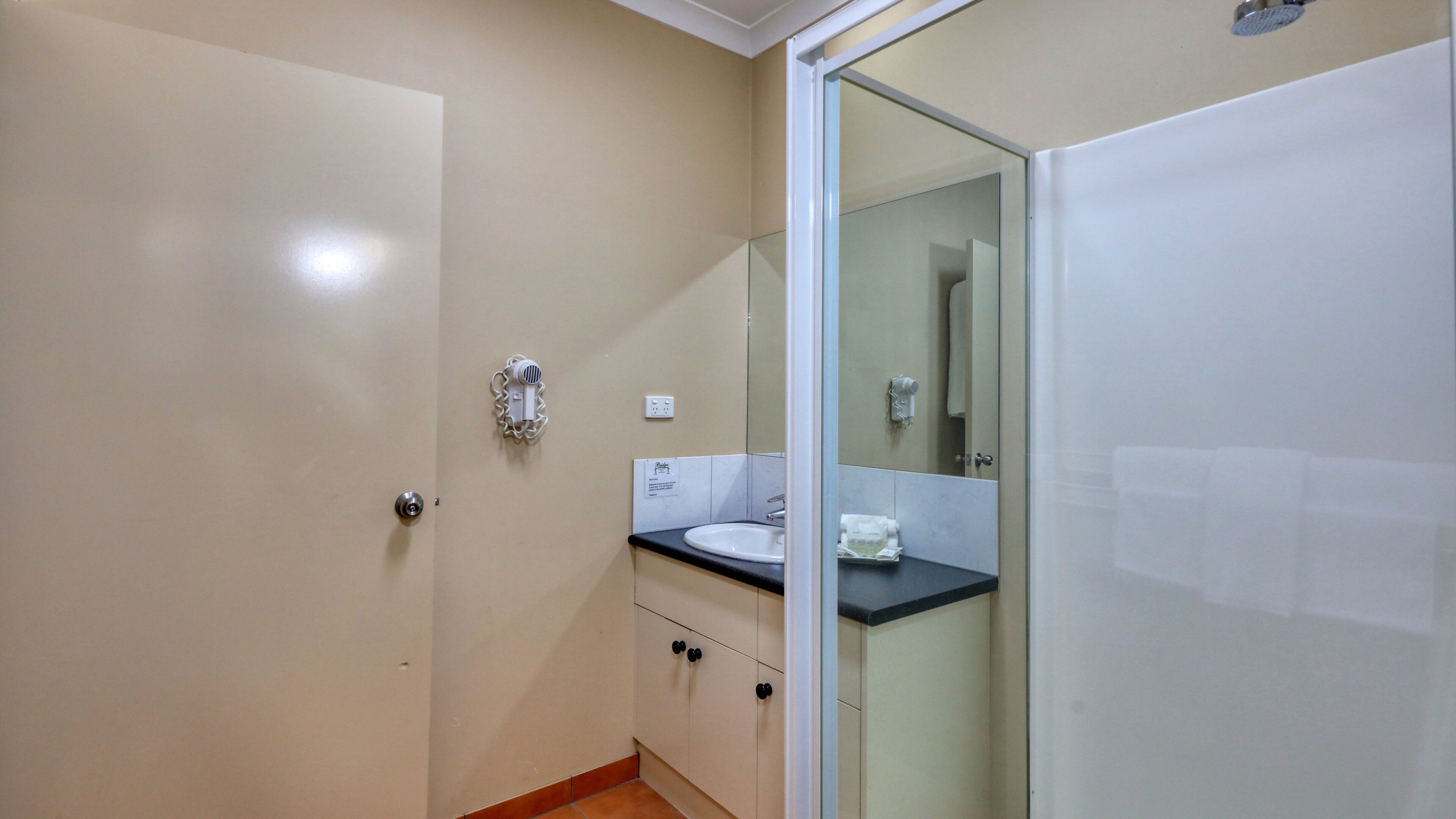 A bathroom with a glass shower enclosure, a sink, and a toilet.