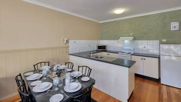 Una cocina compacta con comedor listo para cuatro personas. Incluye microondas, estufa, fregadero y refrigerador.