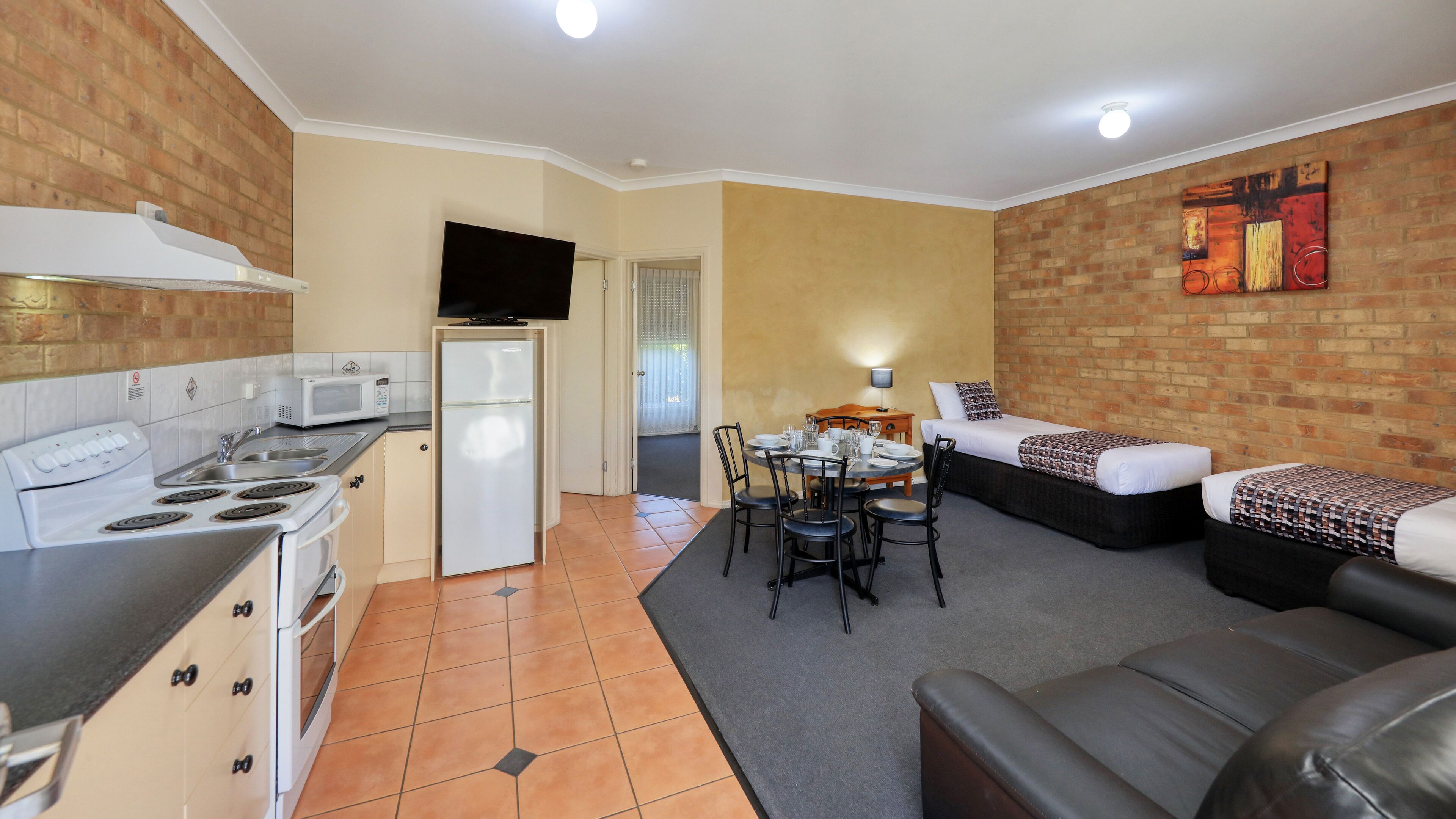 Un espacio habitable compacto con kitchenette, comedor y sofá.