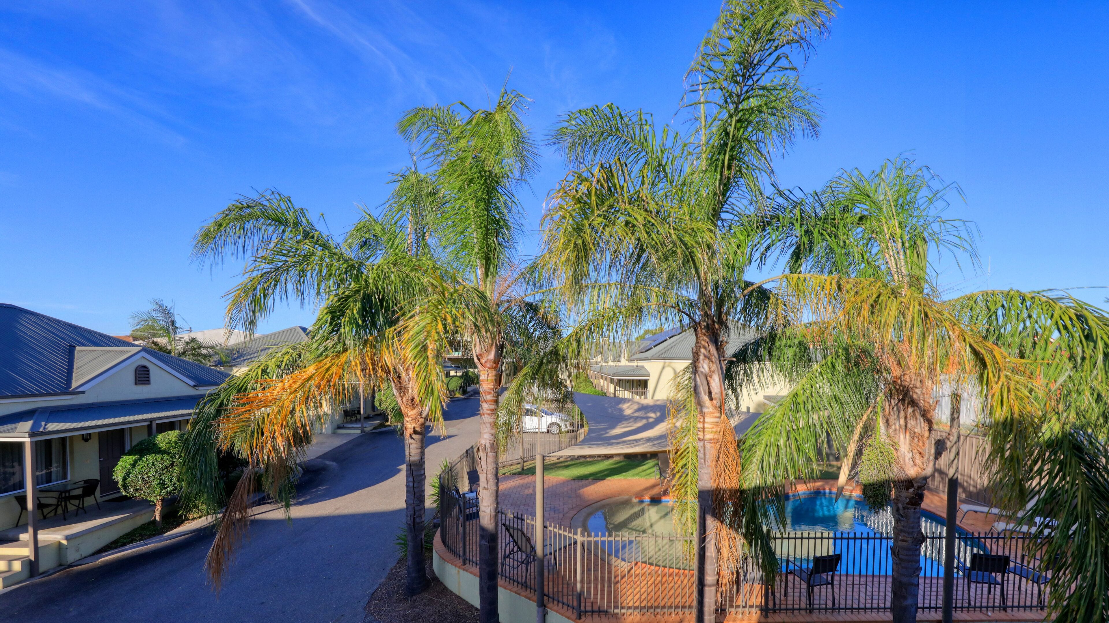 Zona residencial con piscina, palmeras y casas de techos inclinados.