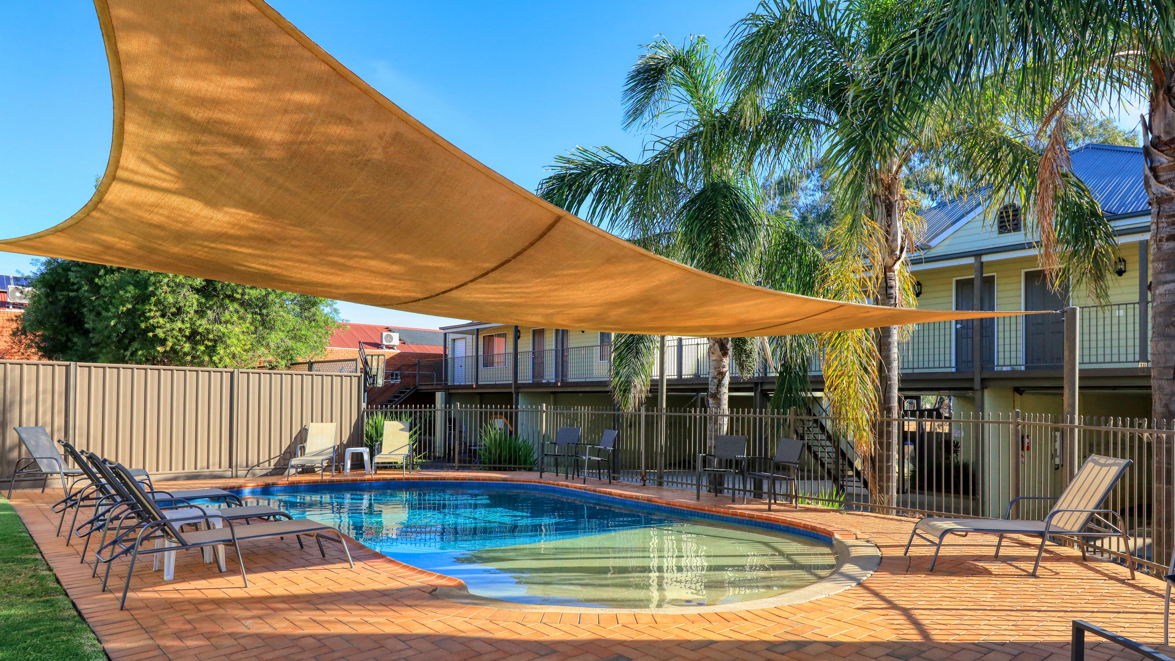 A swimming pool with lounge chairs and a shade sail.