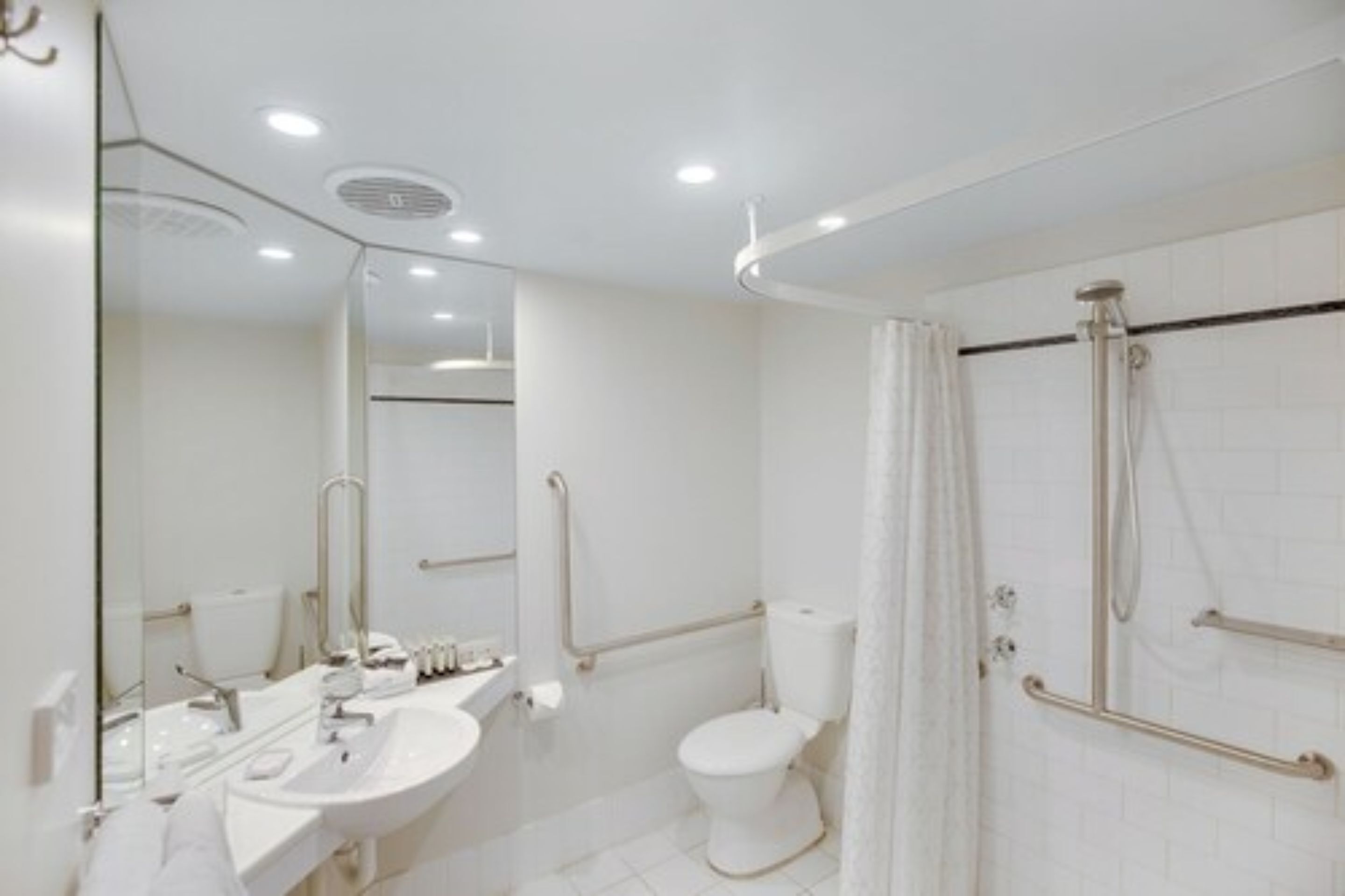 A modern bathroom with a white sink, toilet, and shower area.