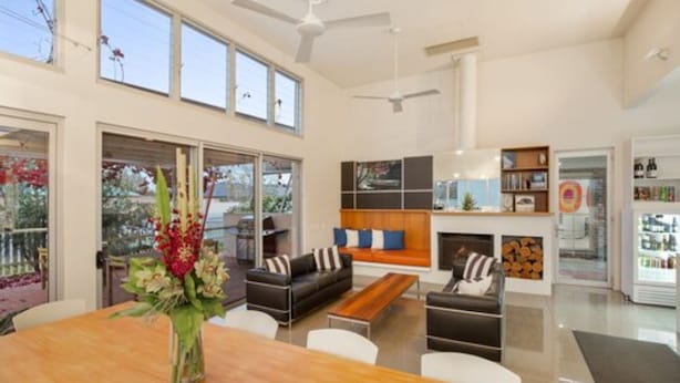 A spacious living area with a wooden dining table, sofas, and a fireplace. There are ceiling fans, a bookshelf, and a refrigerator in the background. - The Horatio - Suites & Motel (Mudgee)