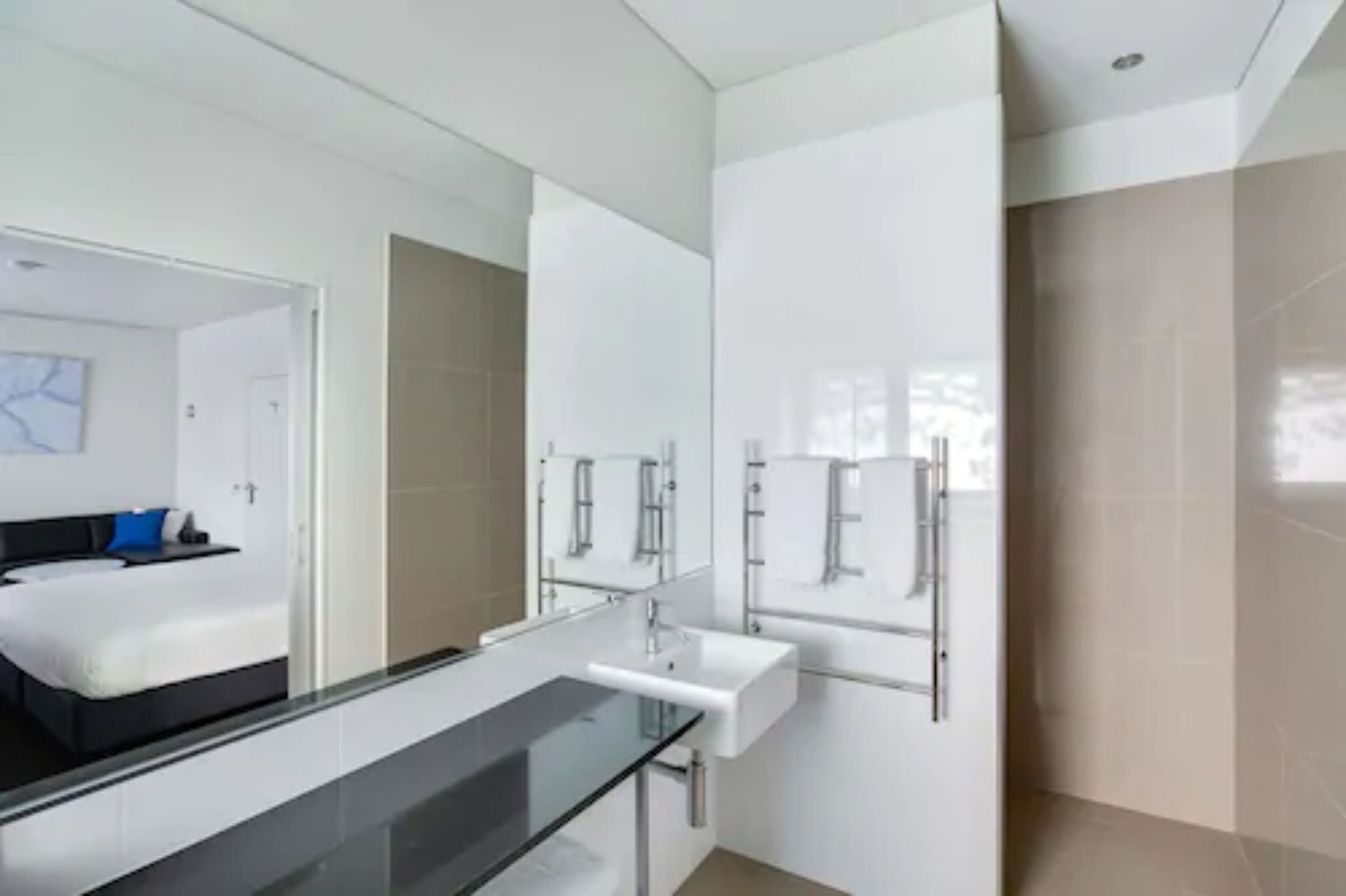 Ein modernes Badezimmer mit Duschkabine aus Glas, einem weißen Waschbecken und einem großen Spiegel.