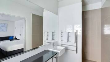 Une salle de bain moderne avec une douche à parois de verre, un lavabo blanc et un grand miroir.