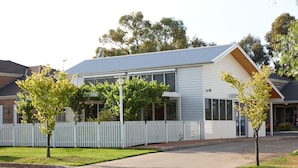 A two-story house with a white picket fence, a front yard, and a driveway. - The Horatio - Suites & Motel (Mudgee)