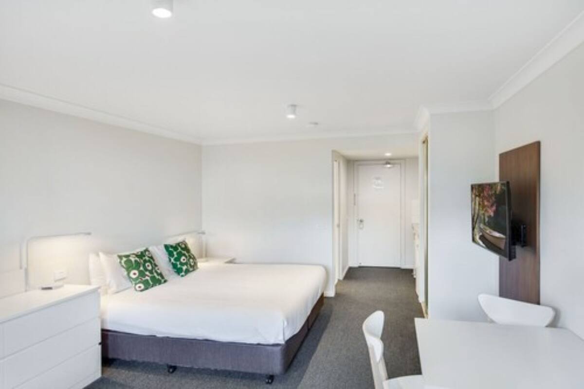 Ein modernes Hotelzimmer mit Bett, Schreibtisch und Fernseher.