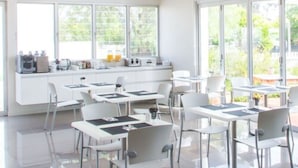 A bright, modern kitchen with large windows, white cabinetry, and a breakfast bar. - The Horatio - Suites & Motel (Mudgee)