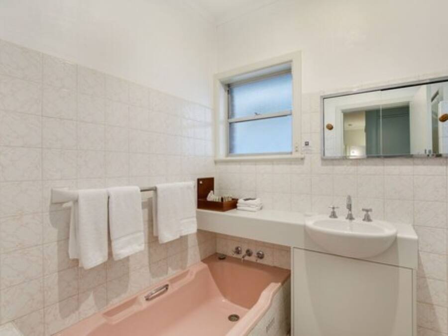 A bathroom with a bathtub, a sink, and a window.