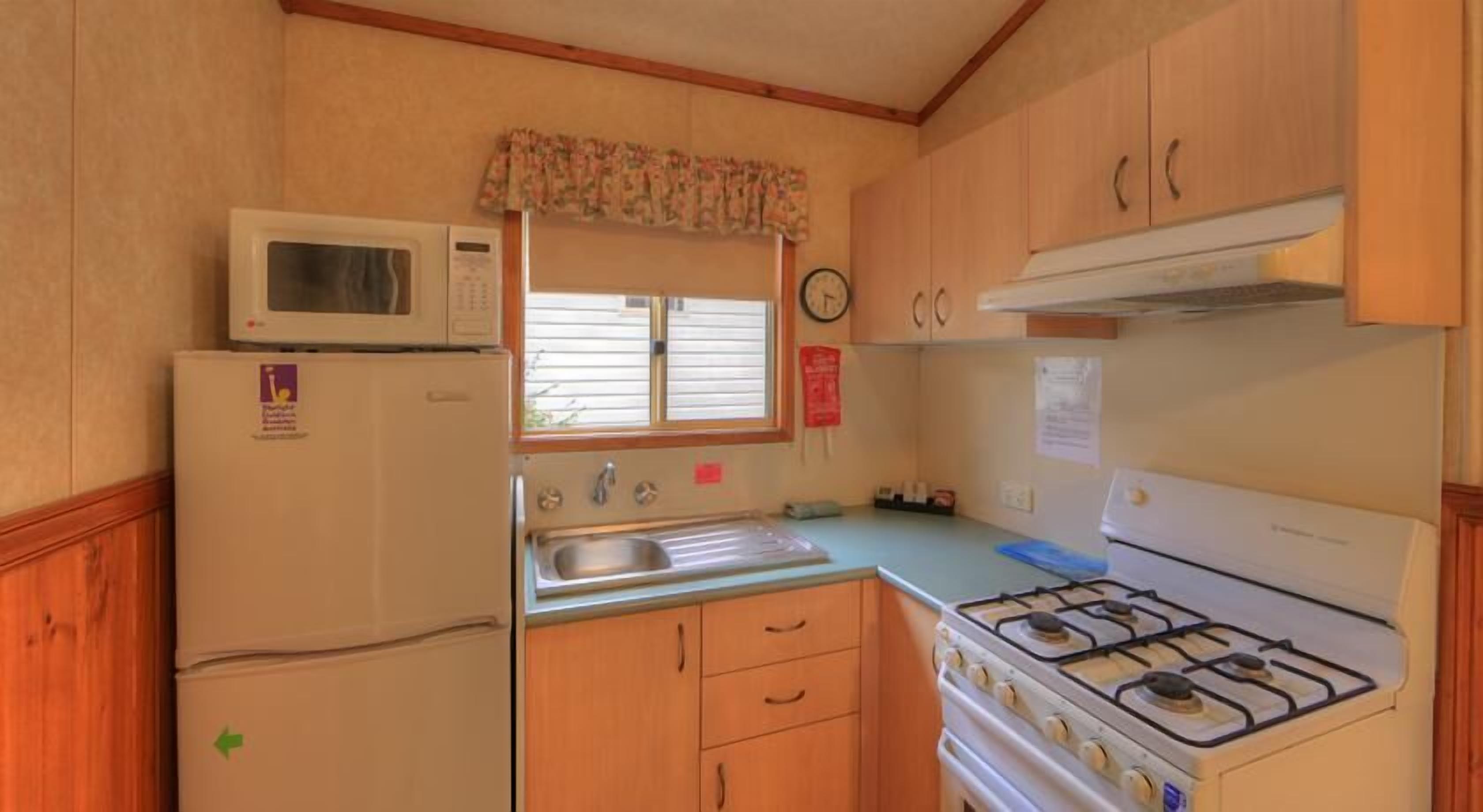 A compact kitchen with a refrigerator, microwave, sink, and stove.