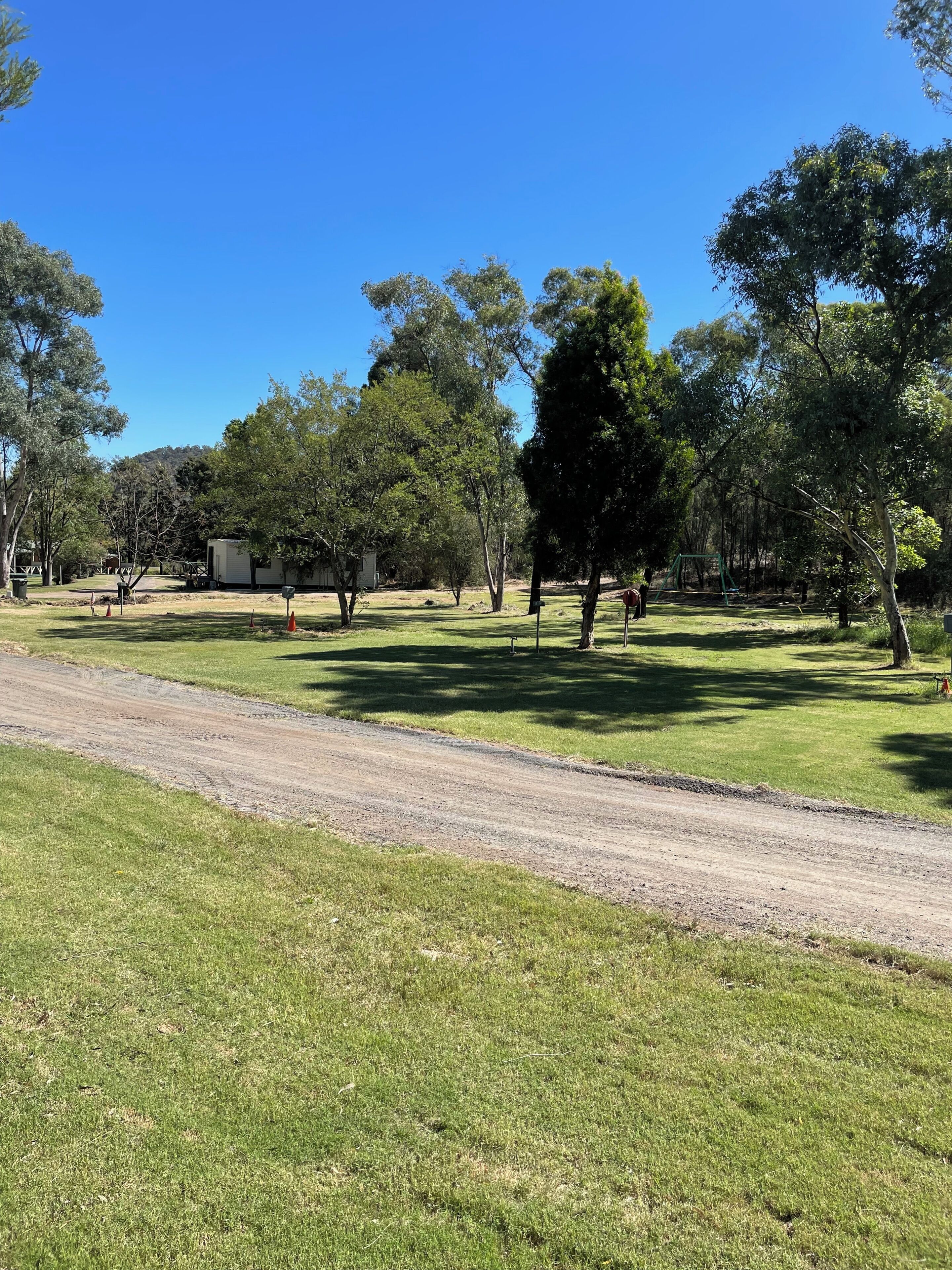 A campground with tents, trees, and a dirt path.