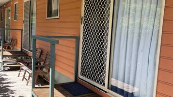 A motel with wooden exterior, multiple windows with mesh screens, and wooden benches along the porch.