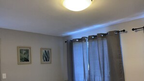 Een net opgemaakt bed met twee handdoeken, een nachtkastje met een lamp en twee ingelijste foto's aan de muur.