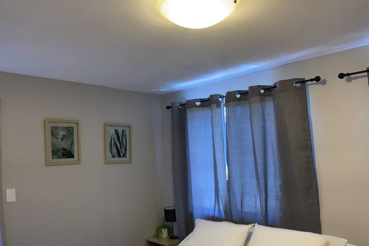 Una cama bien hecha con dos toallas, una mesita de noche con una lámpara y dos cuadros en la pared.