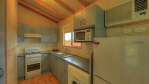 Een kleine keuken met een gasfornuis, oven, magnetron, spoelbak en een wasmachine.