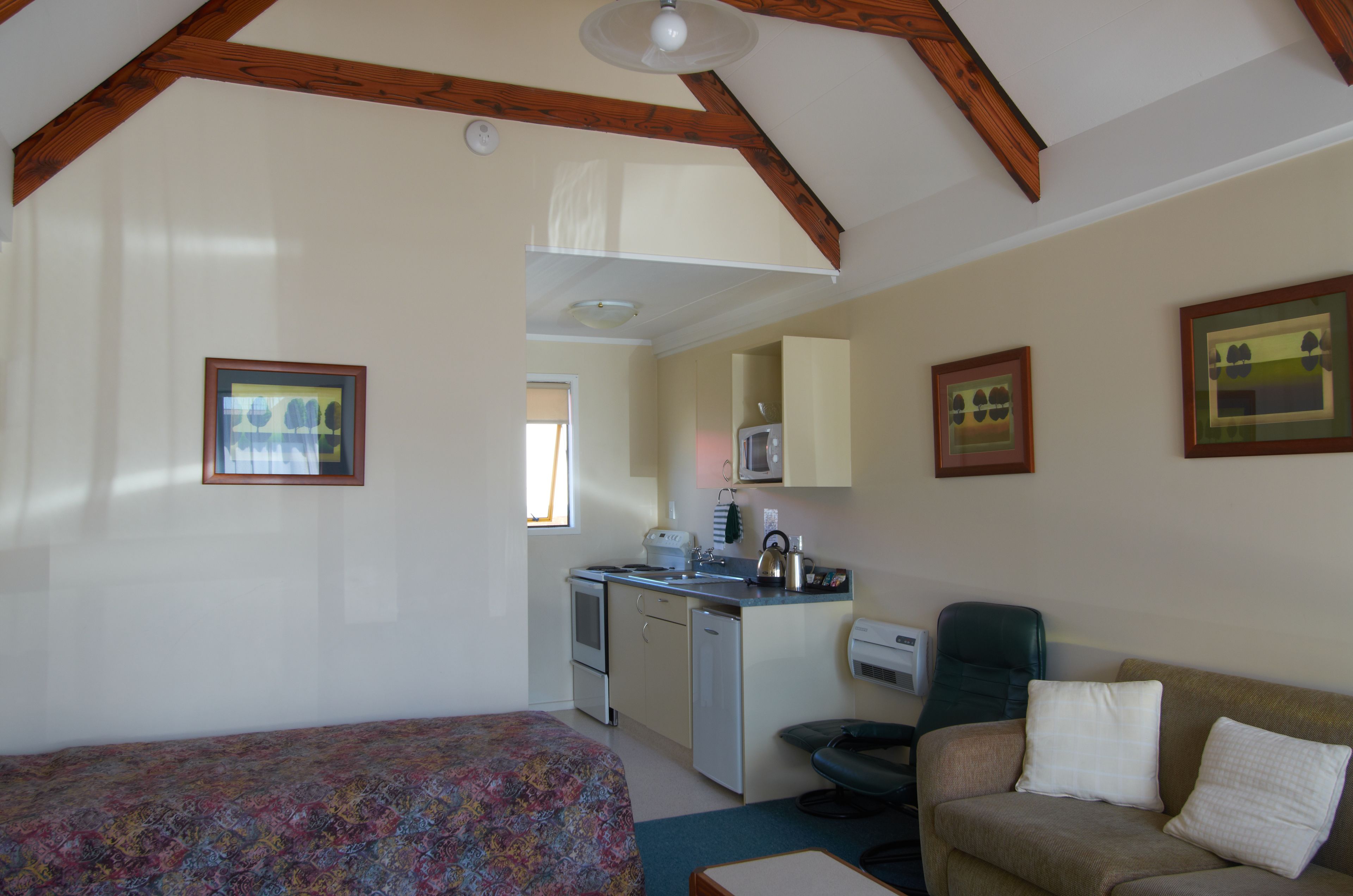 A compact room with a bed, kitchenette, and a sofa.