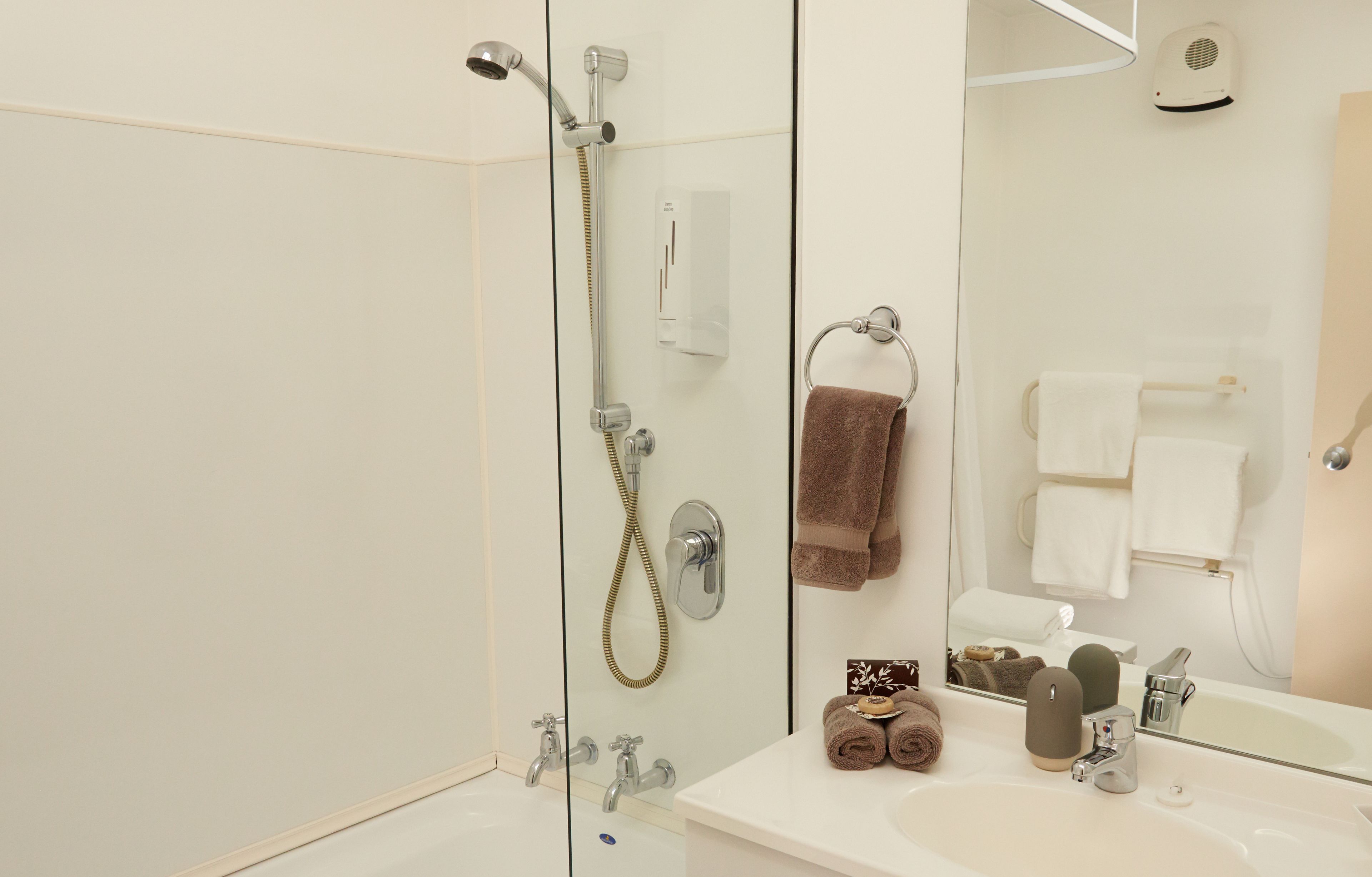 A modern bathroom with a glass-enclosed shower, a white sink, and a large mirror.