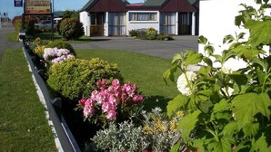 A Bavarian Motel with a red roof and white walls, surrounded by well-maintained gardens with various flowers.