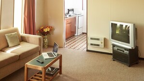 A living room with a sofa, a coffee table with a laptop, a TV, and a fireplace.