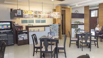 A restaurant with a counter, multiple tables, chairs, and a menu board.