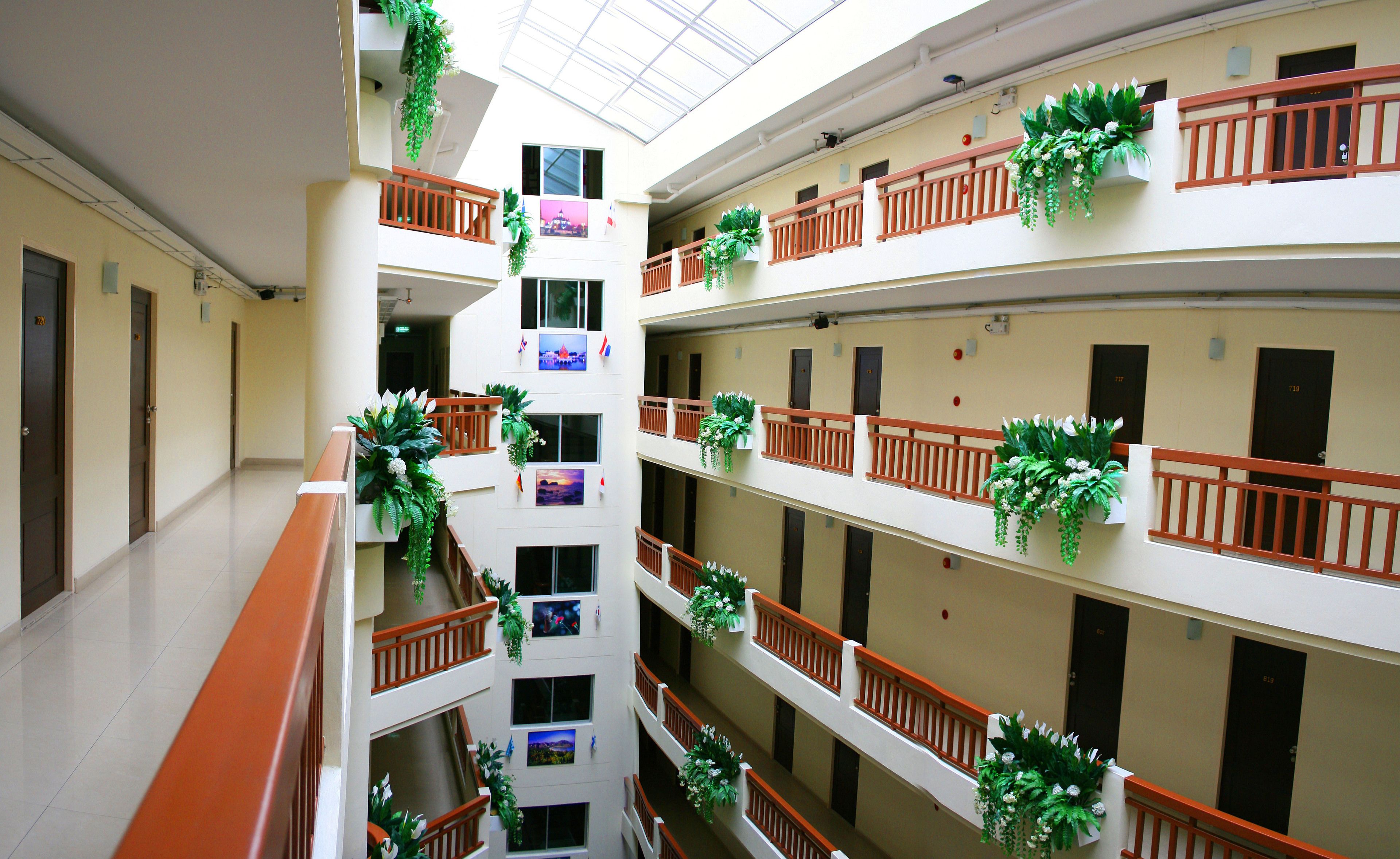 A multi-level hotel atrium with balconies, each adorned with green plants.