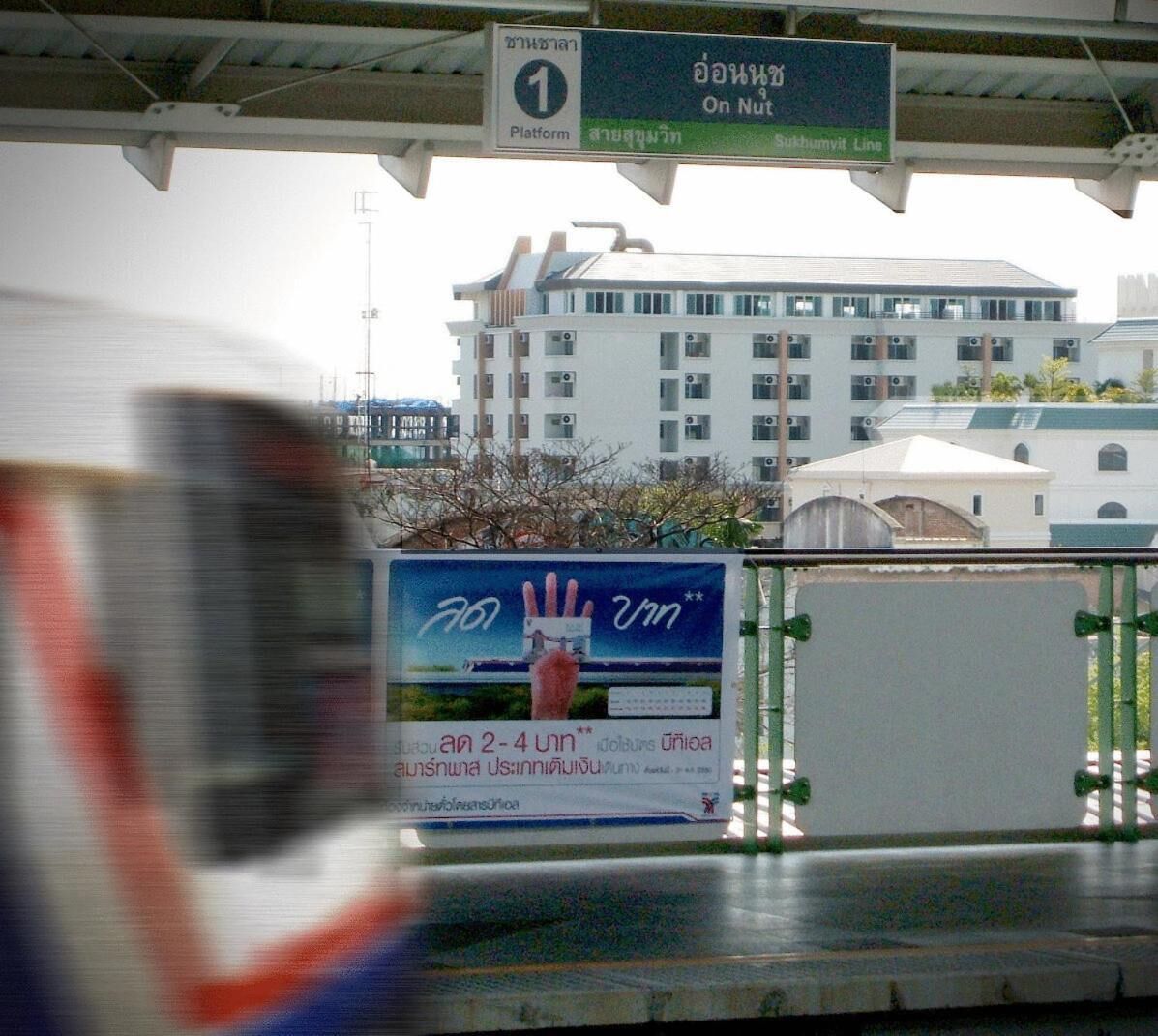 Un andén de estación de tren con un cartel que indica 'Platform 1' y 'Sukhumvit Line'.