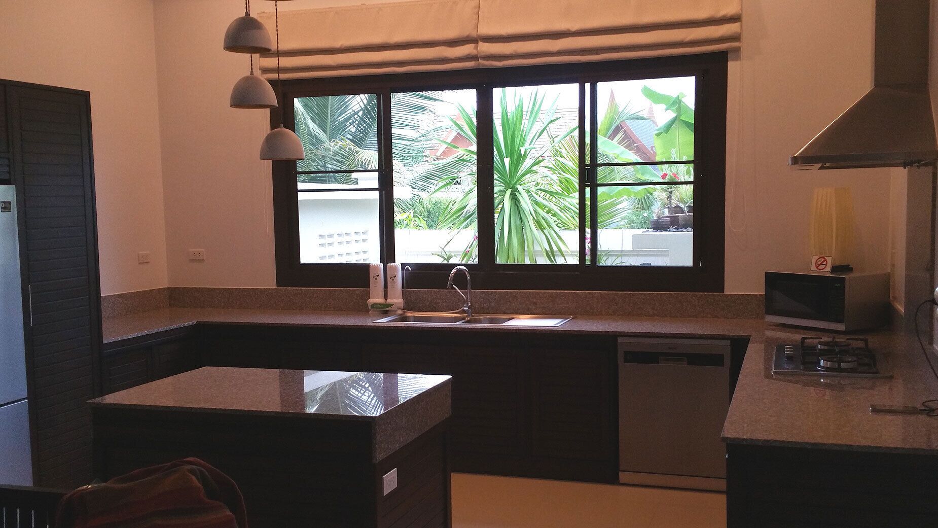A compact kitchen with a built-in dishwasher, a sink, and a microwave.