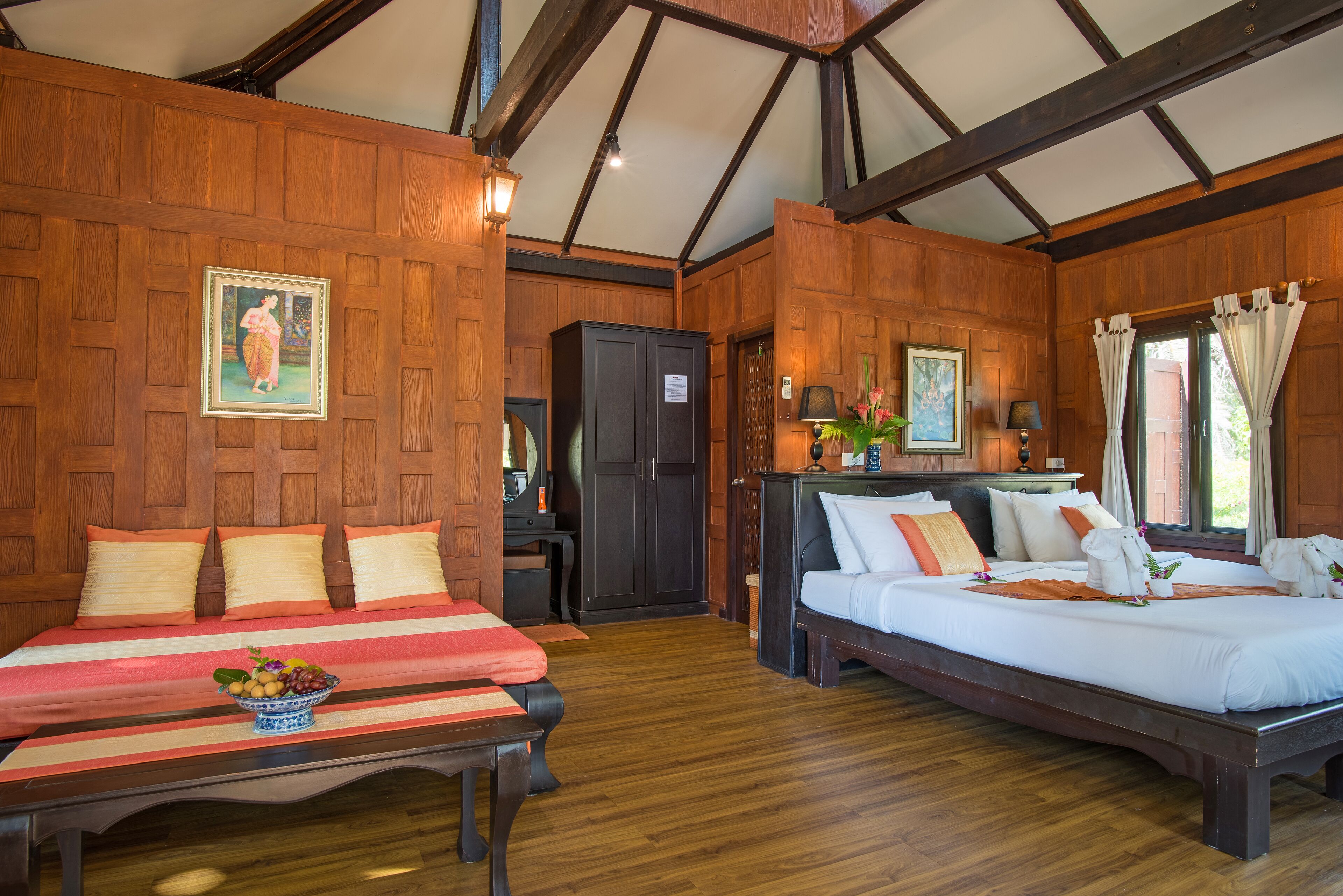 A room with two beds, wooden walls, a wooden ceiling, and a small table with fruit.