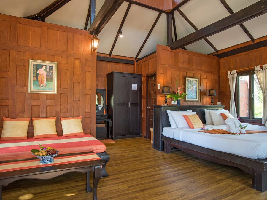 A room with two beds, wooden walls, a wooden ceiling, and a small table with fruit.