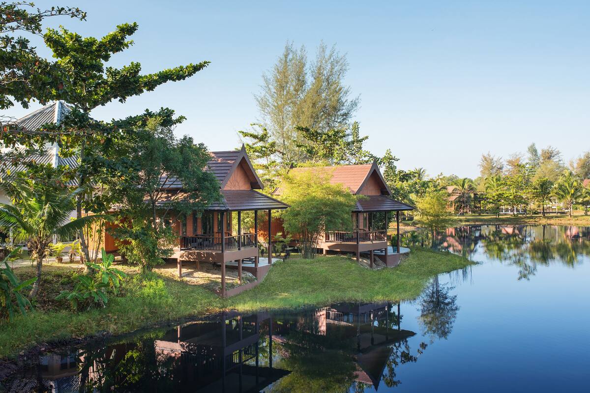 Een rustig gelegen resort aan een meer met houten huisjes, een gazon en een weerspiegeling in het water.